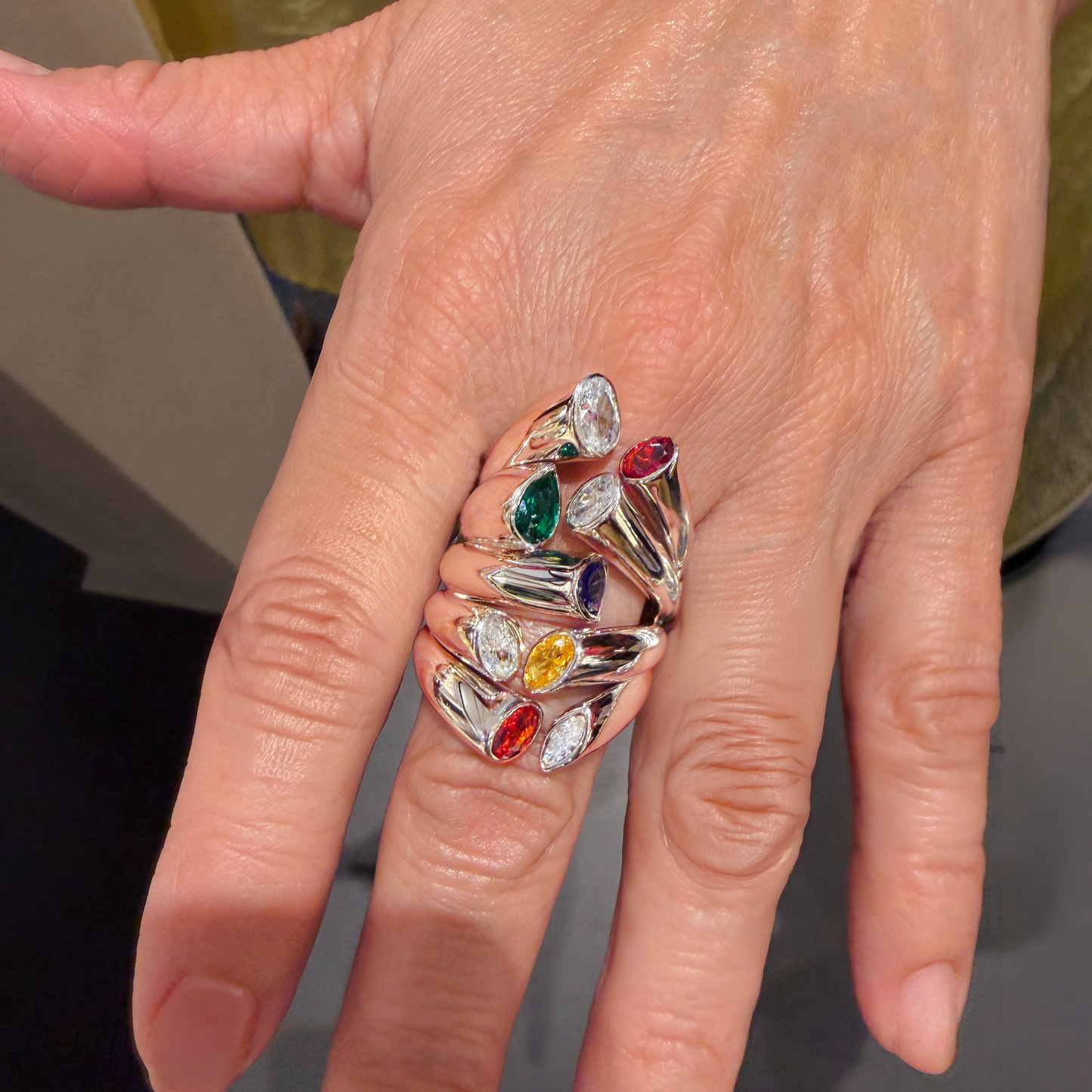 Close-up of a Bella Ring from Dine Collection on hand with colorful gemstone ring with a neutral background- Cocoerow