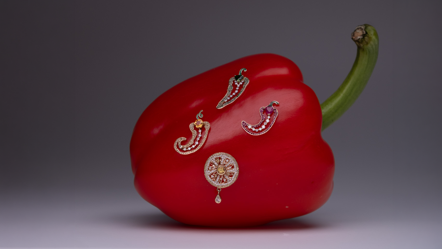 Cocoerow Piri, Aya, Zest, and Rodo earrings in 14k yellow gold styled on a red bell pepper